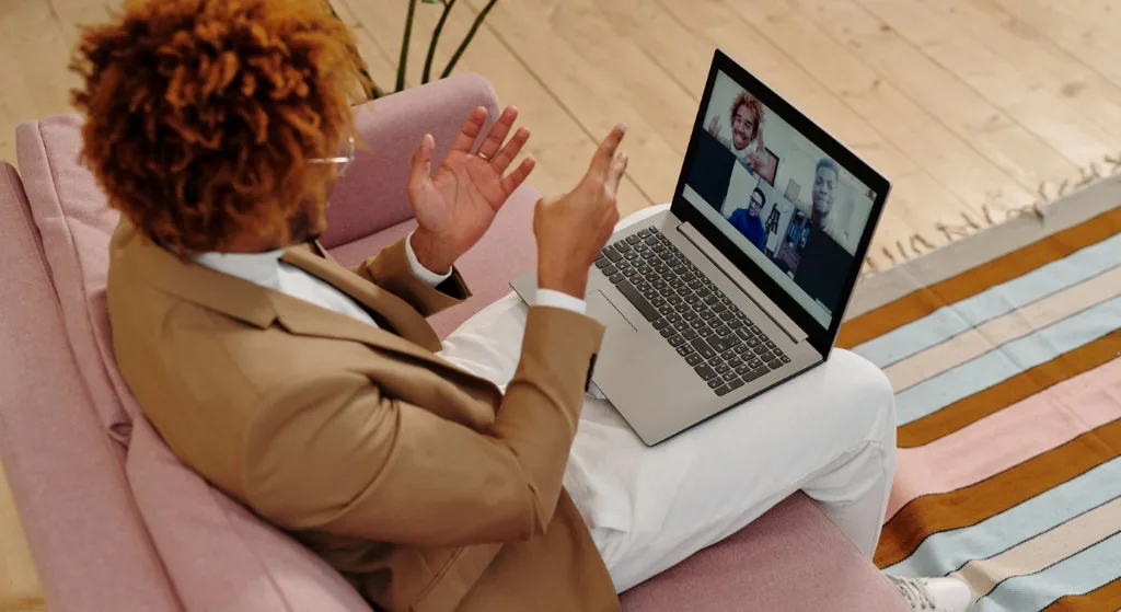 An adult man in a suit engages in a video call while sitting on a sofa indoors